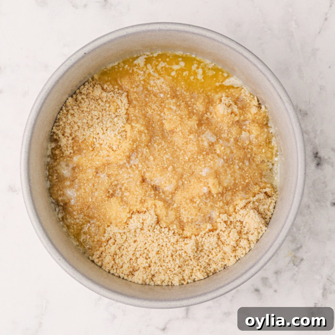 Melted butter combined with crushed golden Oreos in a mixing bowl, ready for the crust.