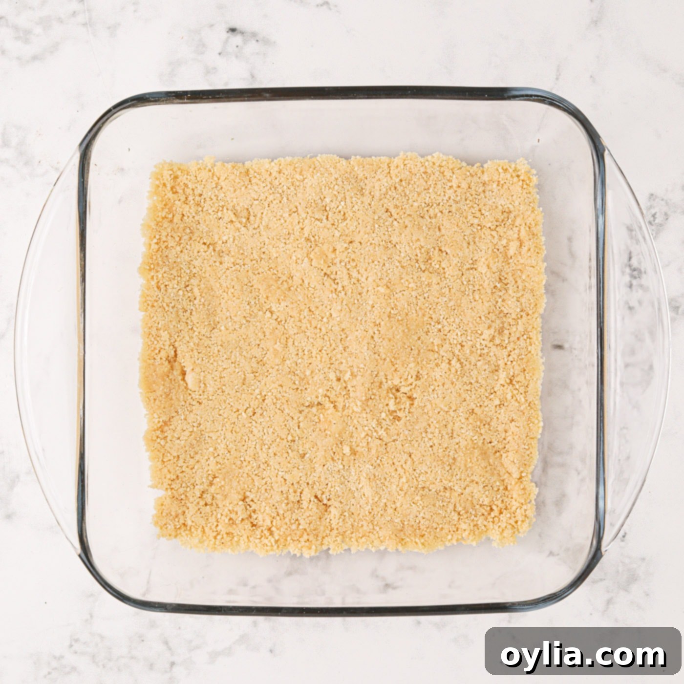 The golden Oreo cookie crust perfectly pressed into the bottom of a baking pan.