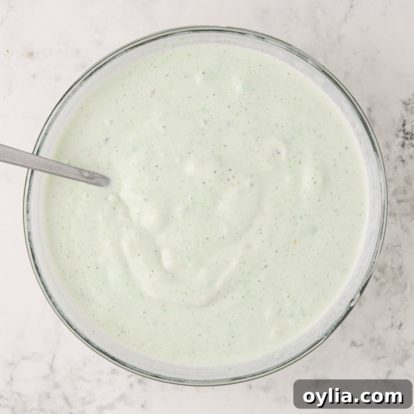 Pistachio pudding mixed with softened vanilla ice cream in a bowl, creating the creamy filling.