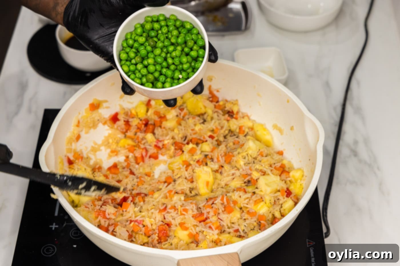 adding peas to skillet with fried rice