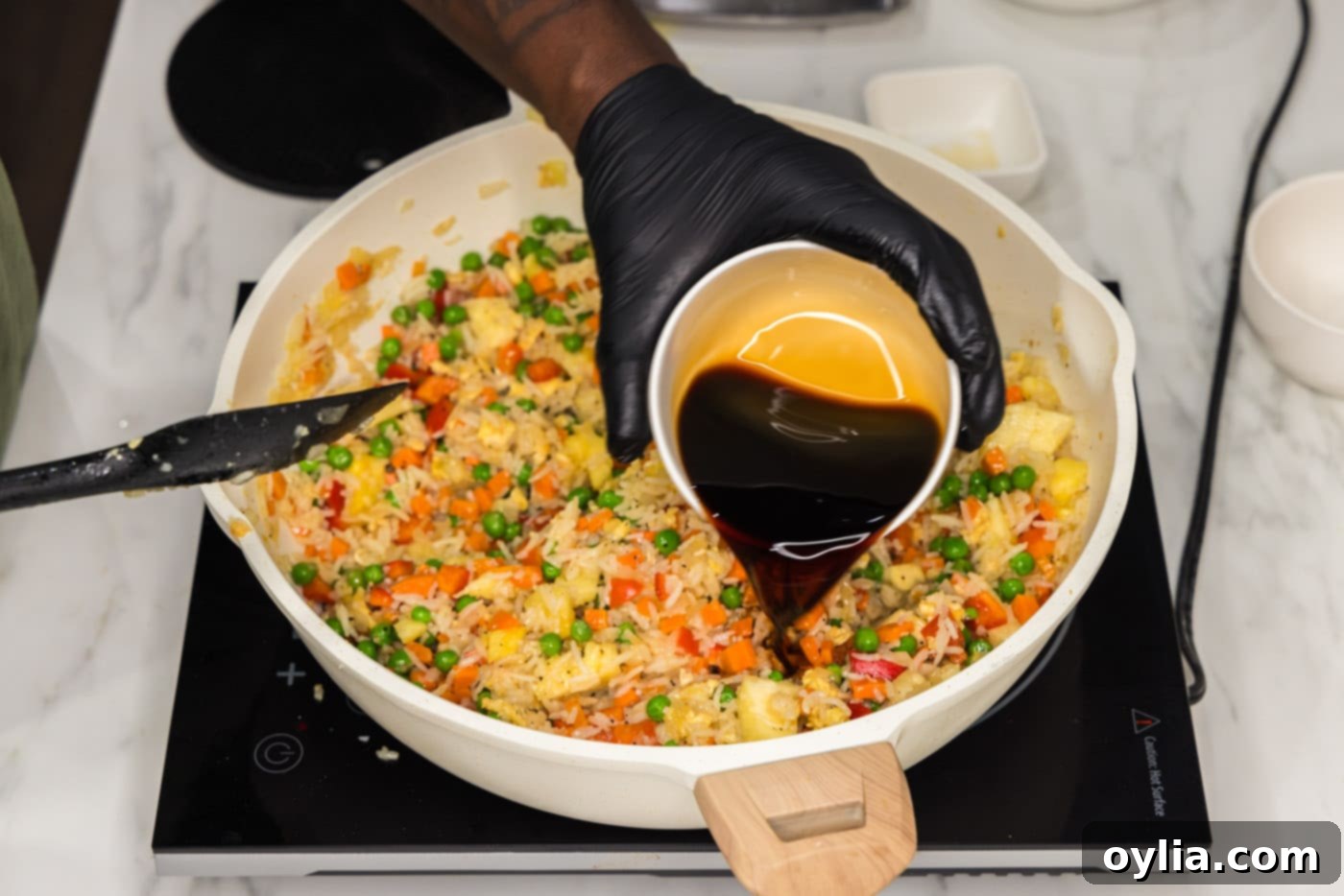 pouring soy sauce into skillet with pineapple fried rice
