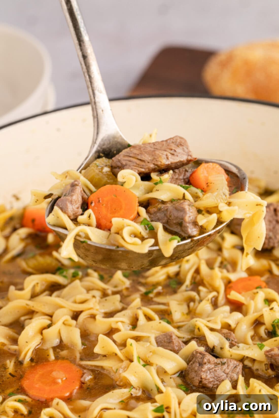 Hearty Beef Noodle Bliss 3 Ladle of Beef Noodle Soup held above a pot of bubbling soup, showcasing tender beef and vegetables