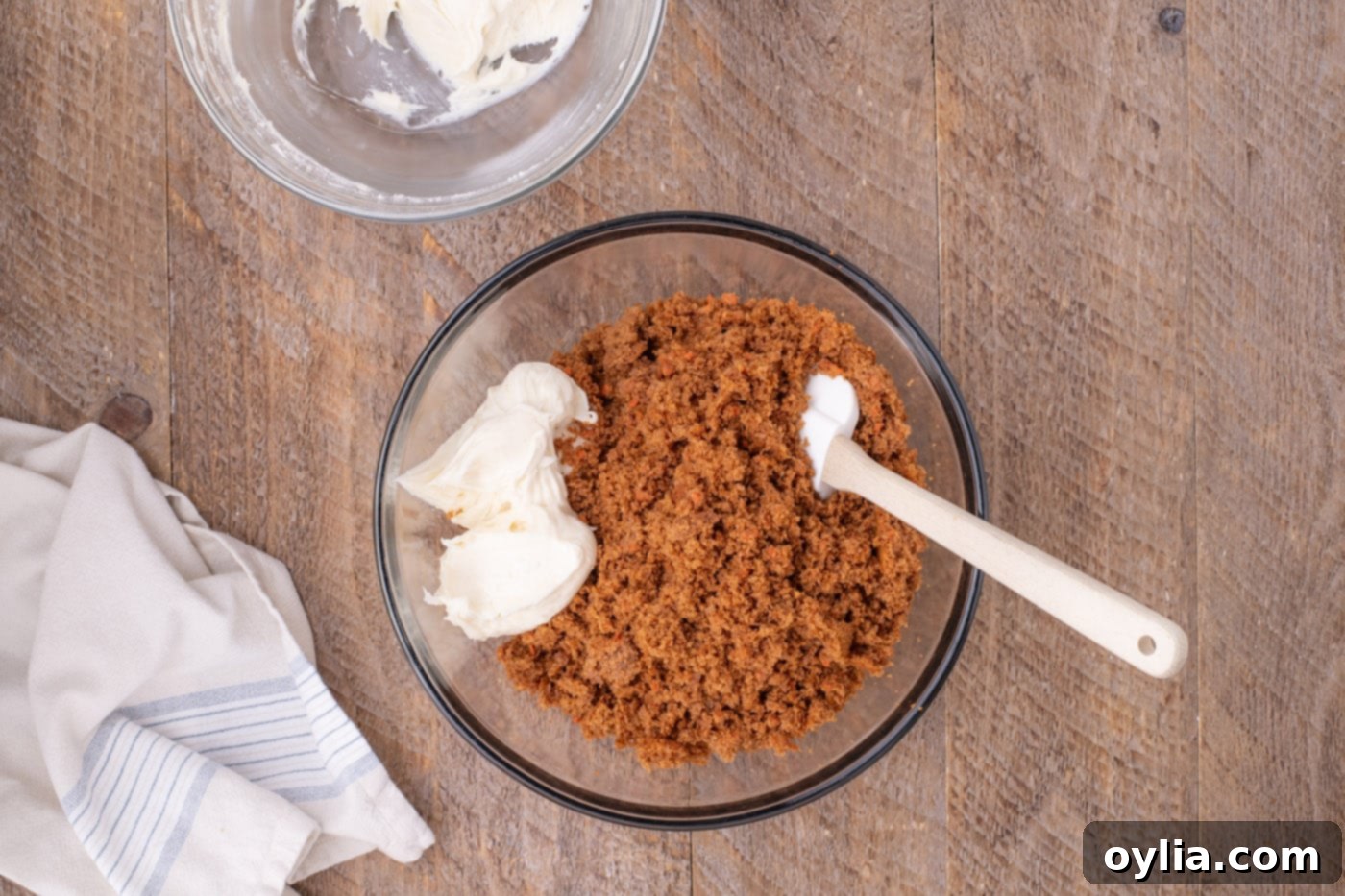 combining cream cheese frosting with crumbled carrot cake
