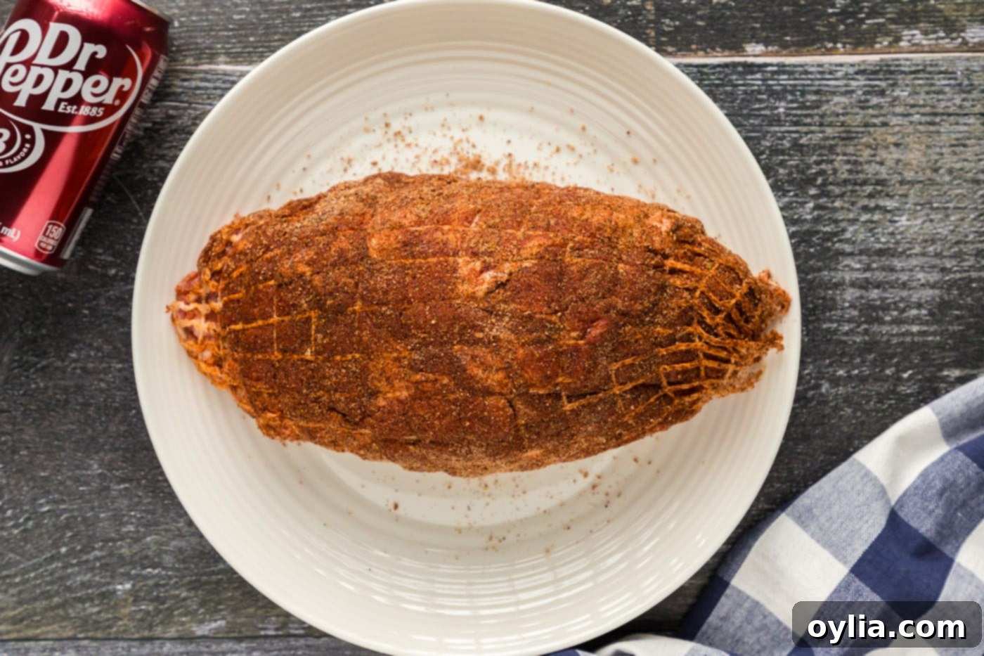 A boneless pork shoulder generously coated with a dark, aromatic dry rub, ready for searing.