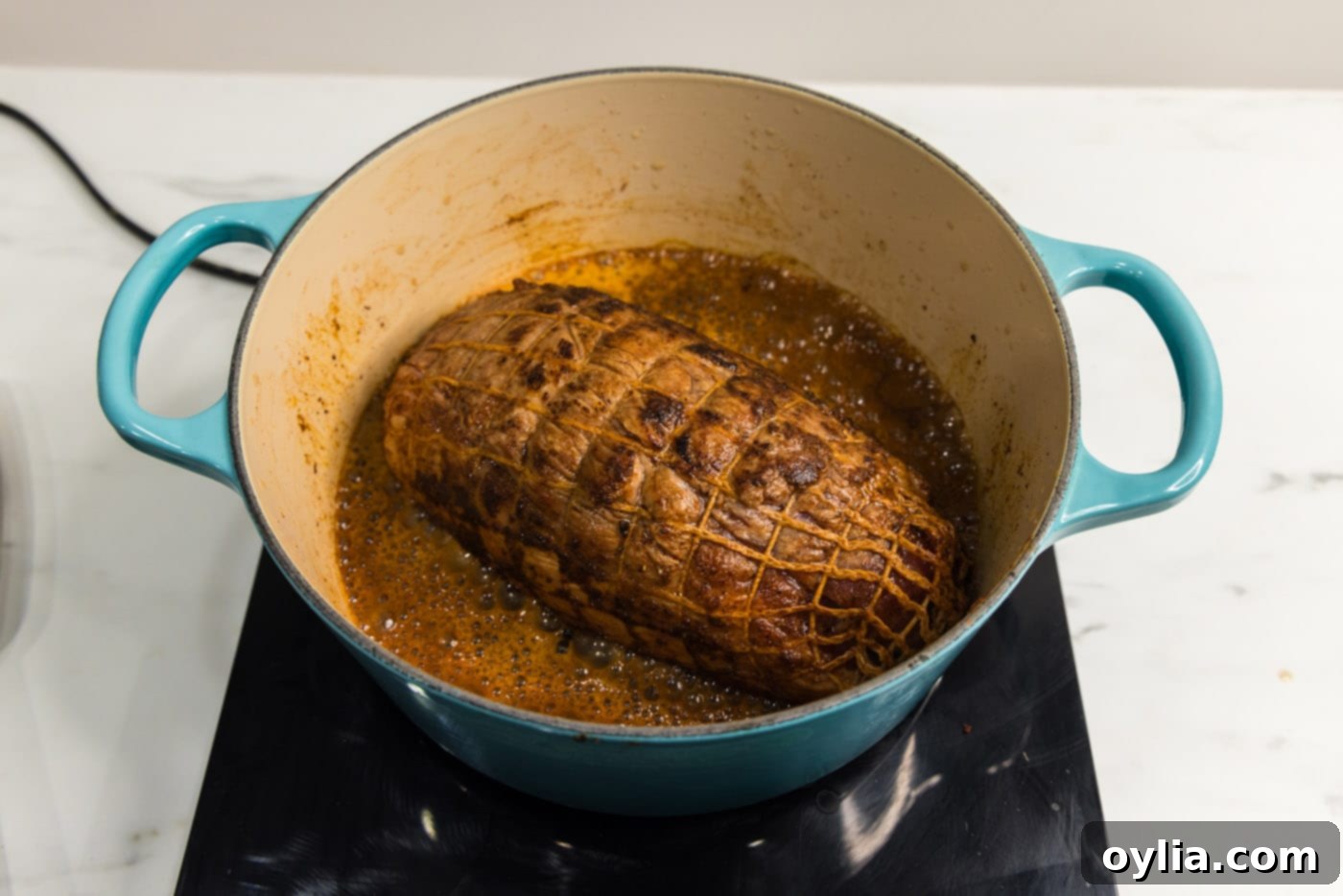 A Dutch oven with a lid, containing the pork shoulder and Dr. Pepper, placed inside an oven for slow cooking.