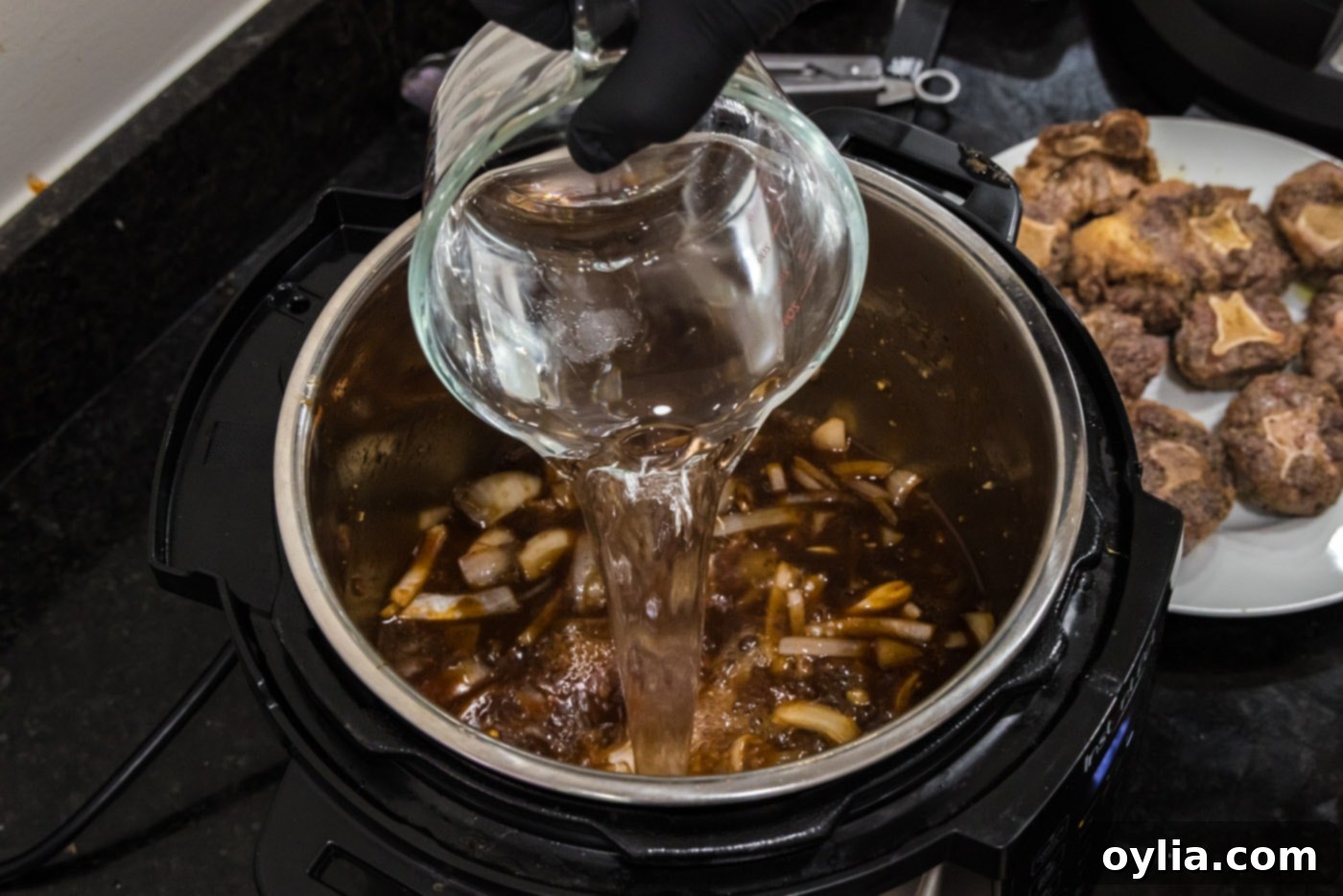 pouring water into instant pot oxtail stew