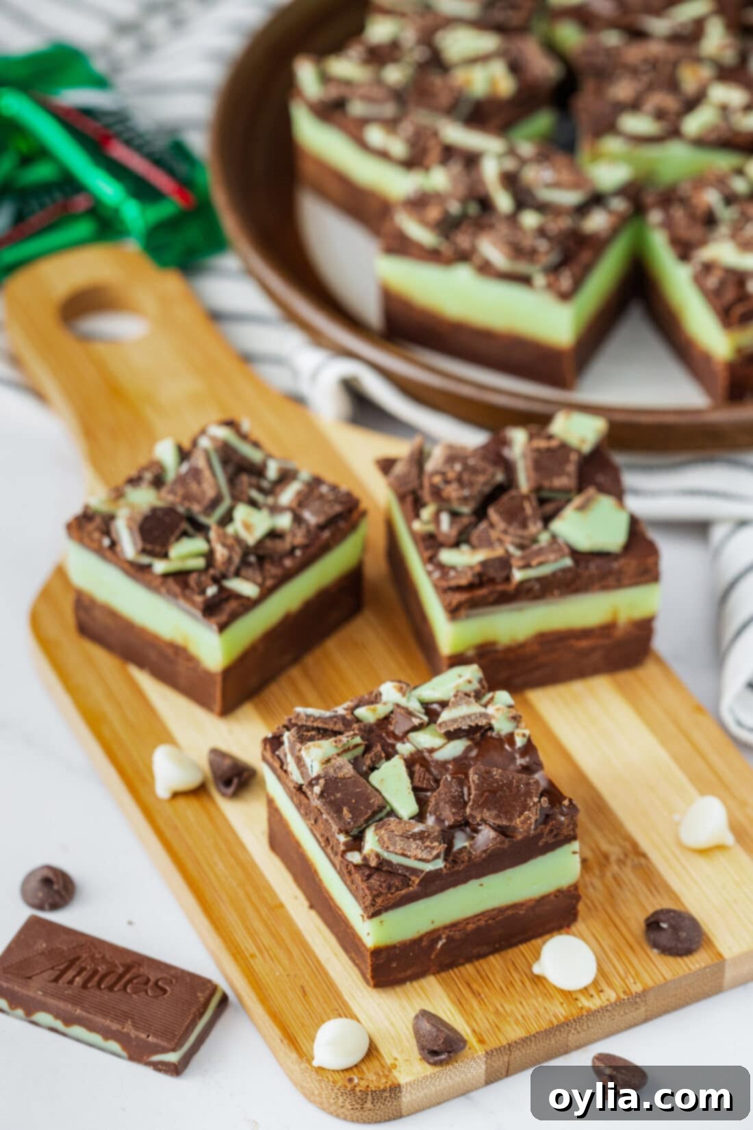 Andes Mint Chocolate Fudge 3 Three perfectly cut squares of Andes Mint Fudge displayed on a rustic wooden board, highlighting the distinct chocolate and mint layers