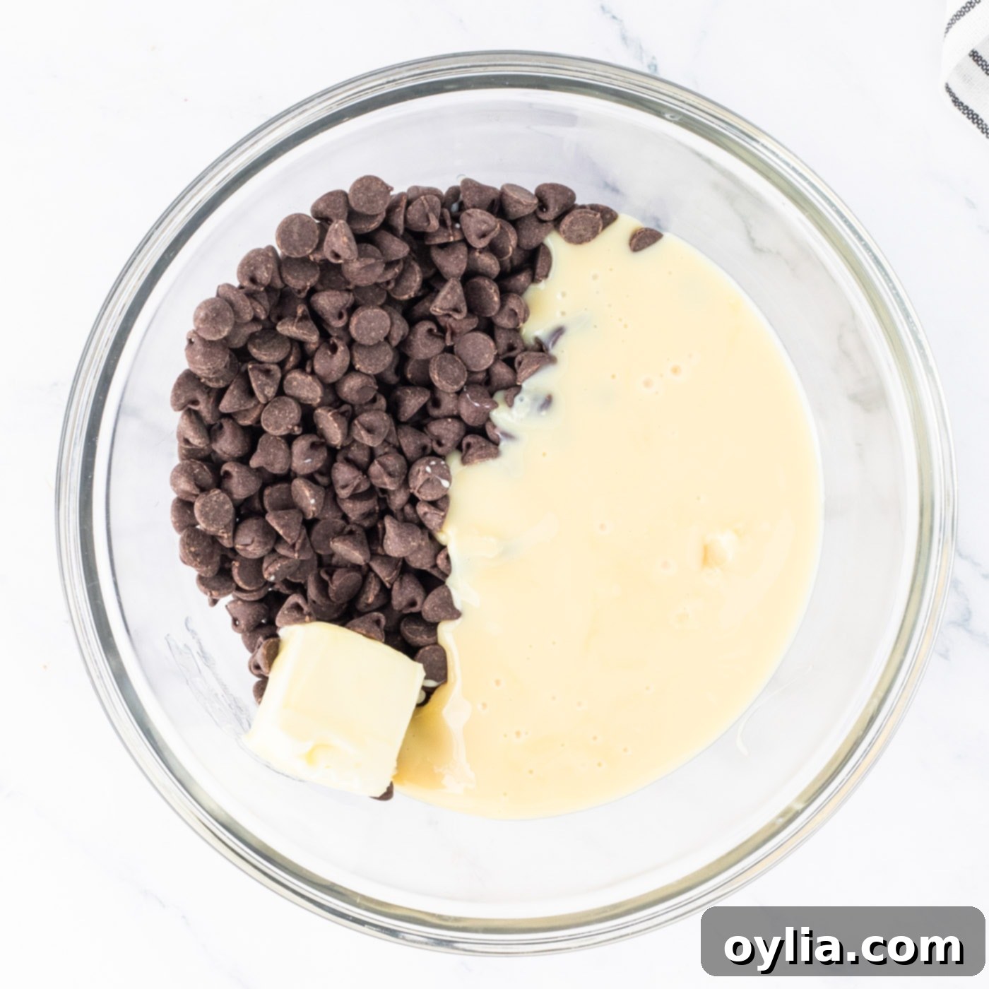Semi-sweet chocolate chips, butter, and sweetened condensed milk in a bowl before microwaving for the first fudge layer