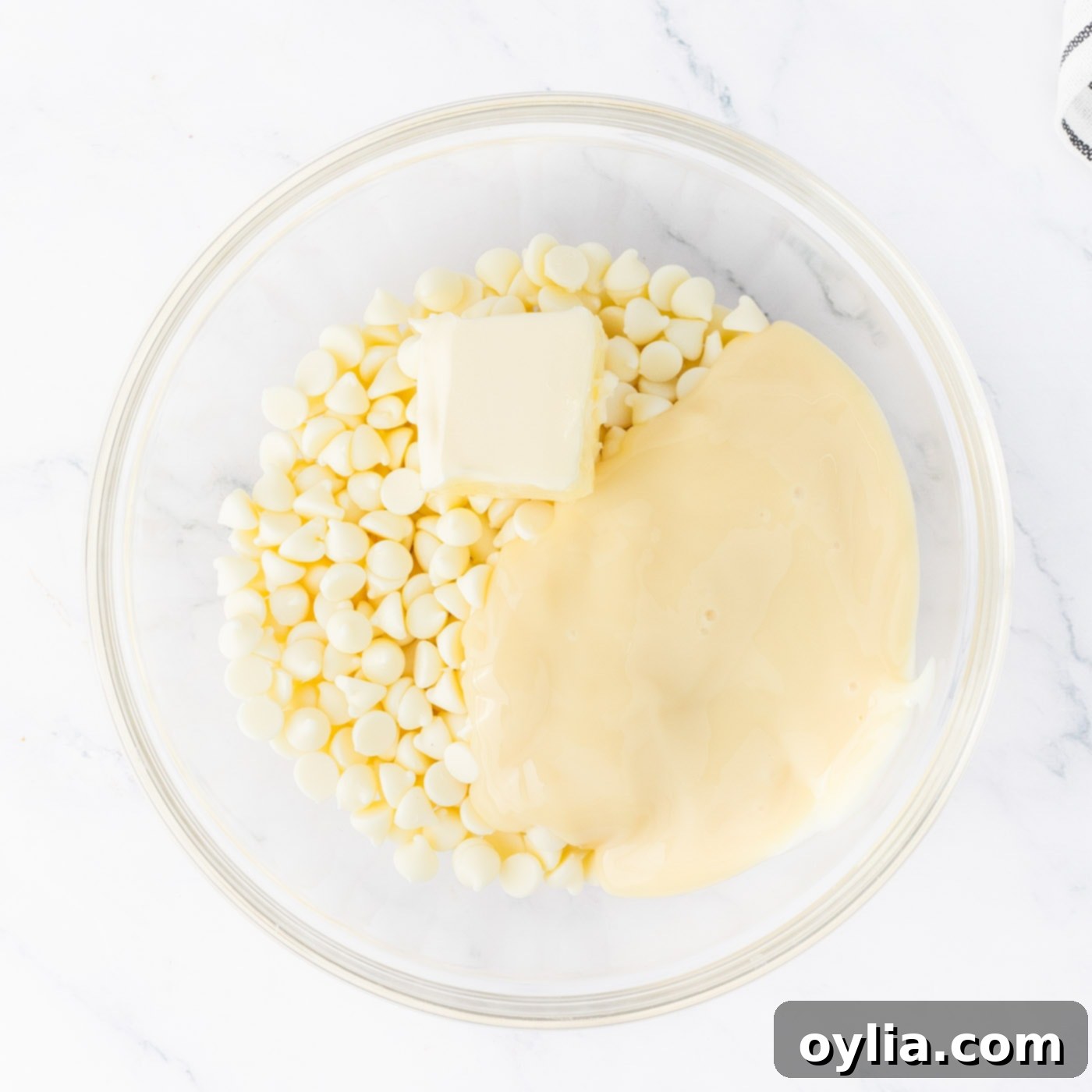 White chocolate chips, sweetened condensed milk, and butter in a bowl ready for microwaving to create the mint fudge layer