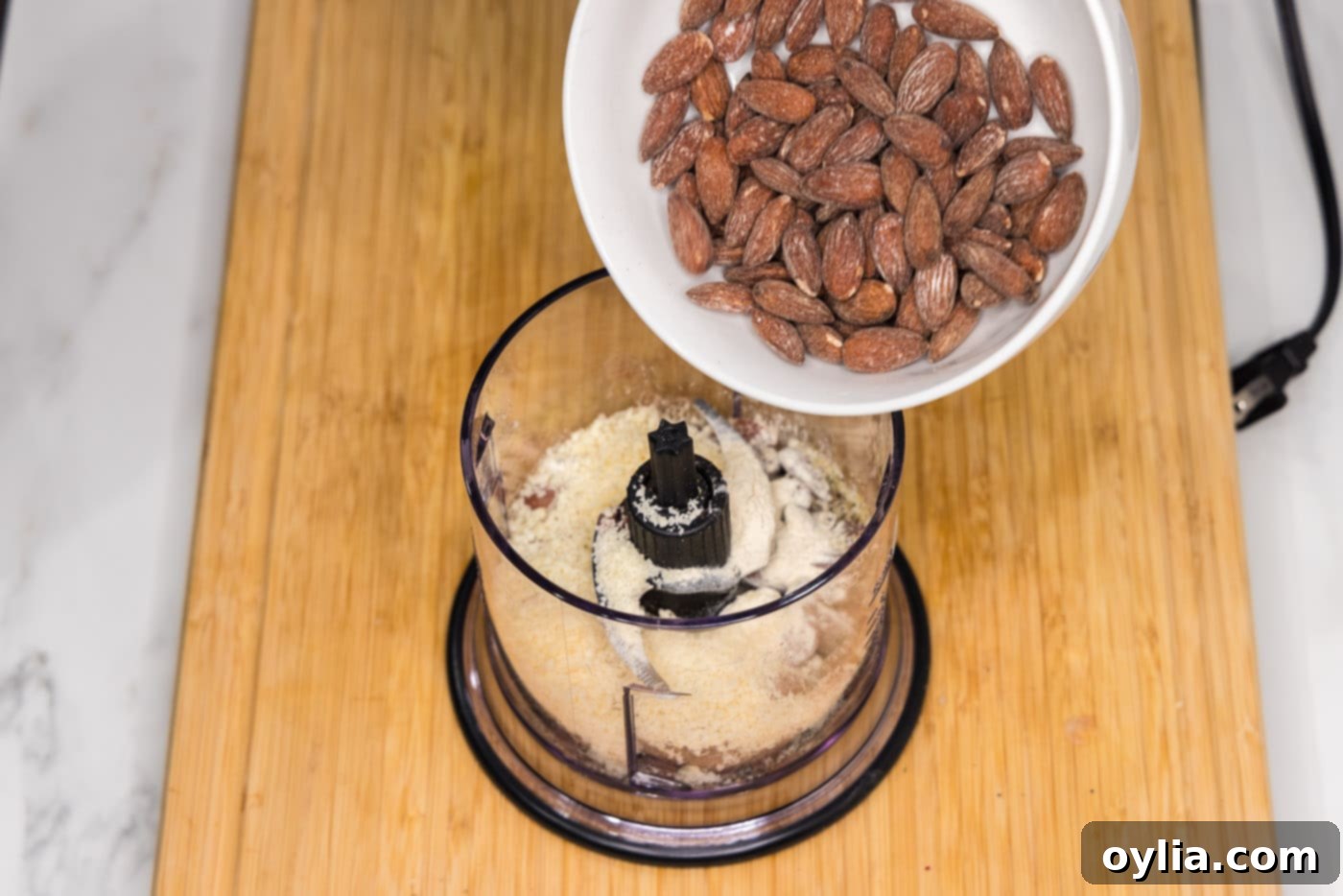 pouring almonds into food processor with seasonings and parmesan cheese