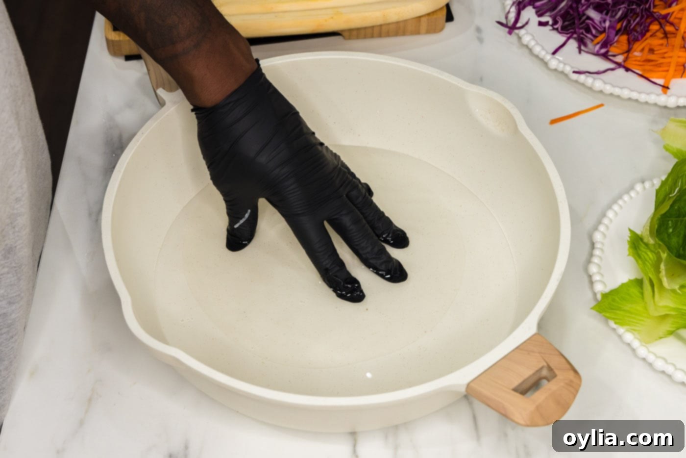 spring roll wrapper dipped in a skillet of water, softening for rolling