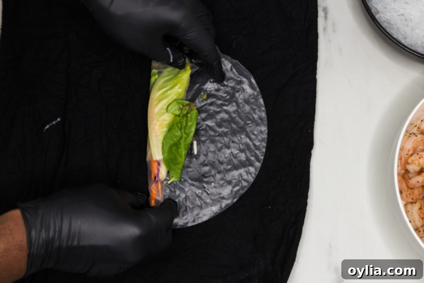 wrapping vegetables in a spring roll wrapper, preparing to add shrimp
