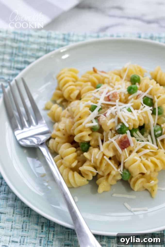 Rotini with peas and cheese in a bowl, garnished with bacon