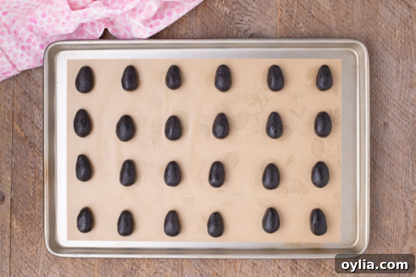 Easter egg shaped Oreo truffles neatly arranged on a parchment-lined baking sheet