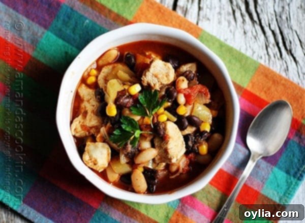 An inviting overhead photo of a steaming bowl of chicken chili, rich with black beans and corn.