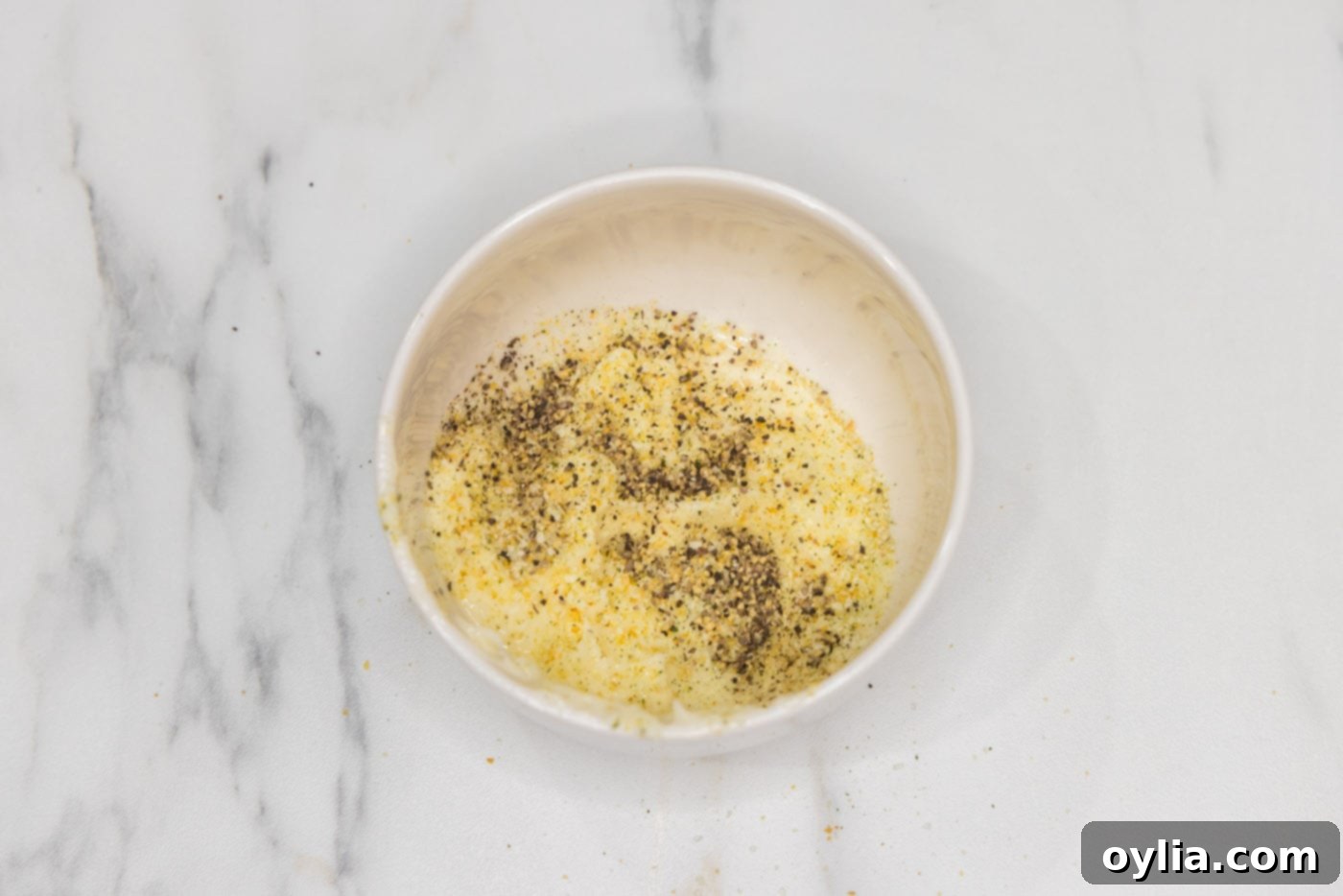 mixing softened butter with garlic salt and pepper in a bowl
