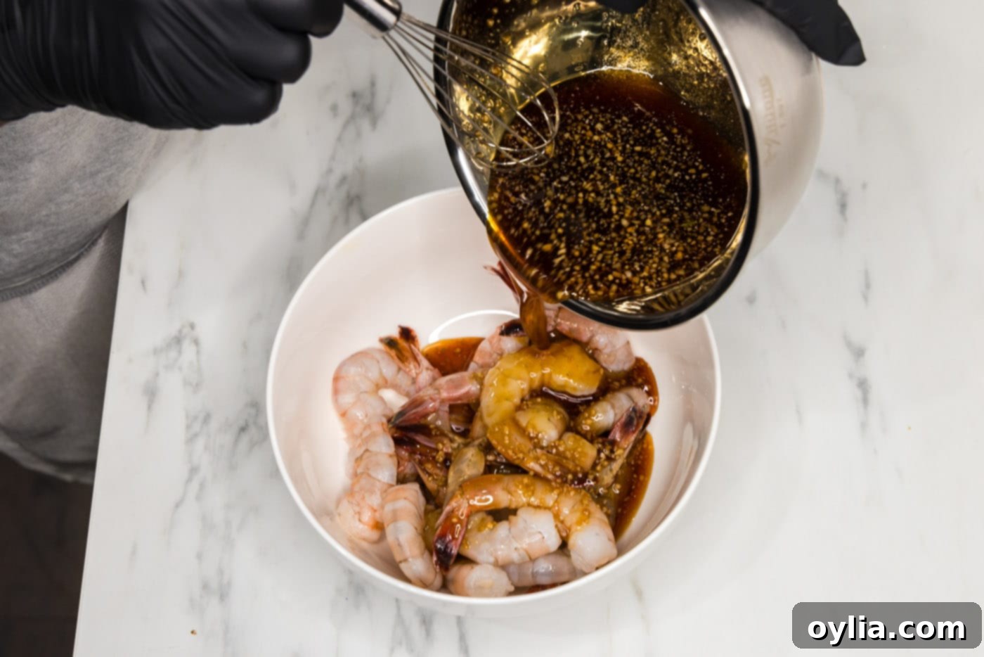 pouring honey garlic sauce over shrimp in a bowl