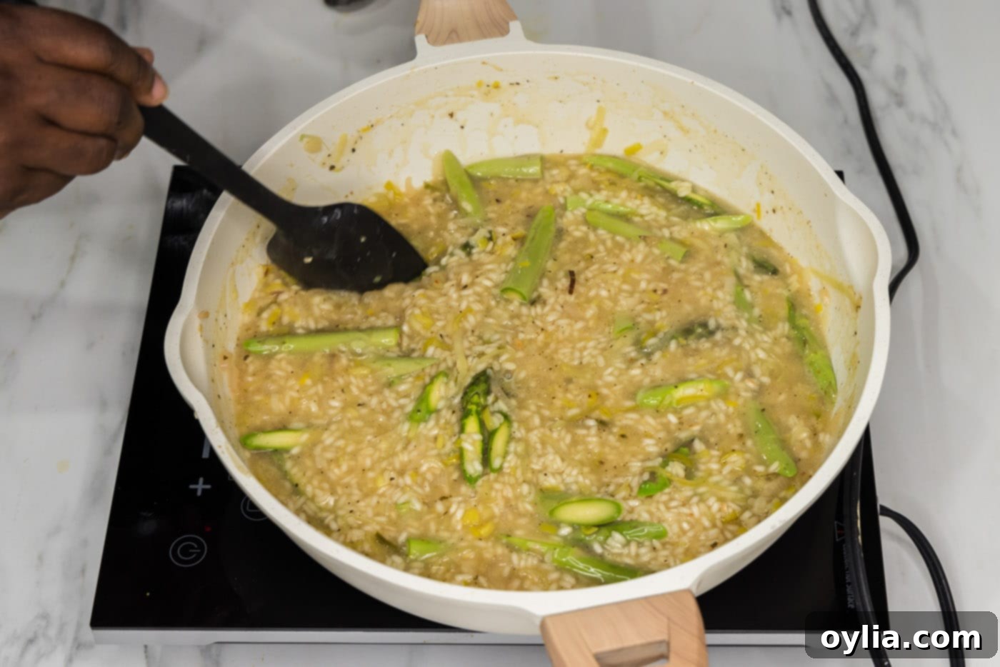 turning asparagus spears in a skillet with creamy risotto