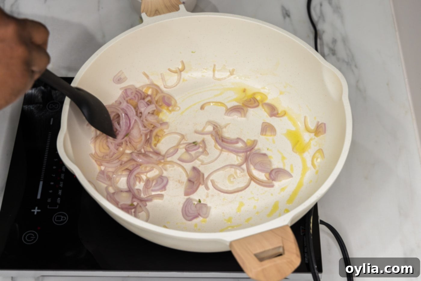 sliced shallots cooking in a pan of olive oil