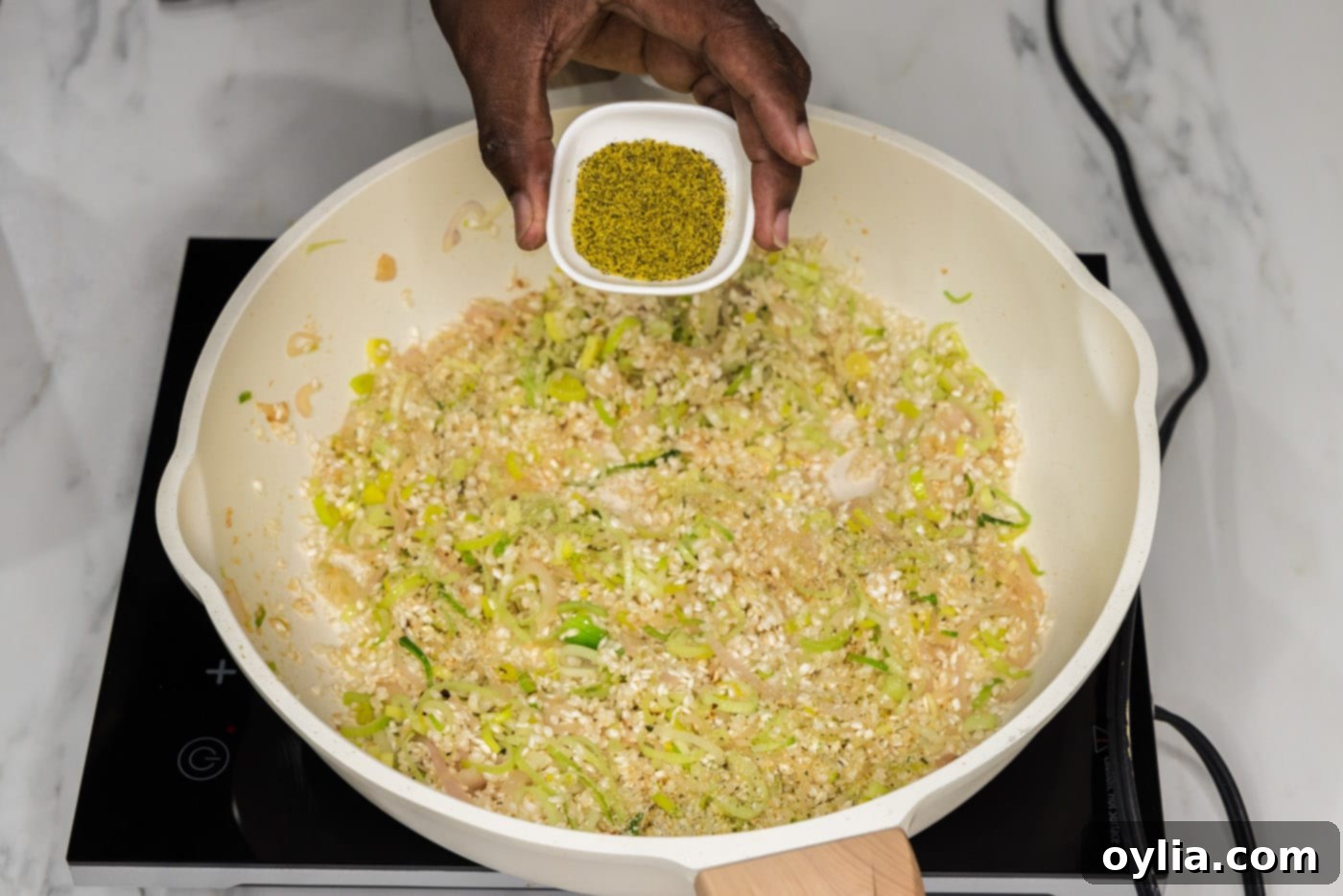 adding lemon pepper to risotto in a skillet