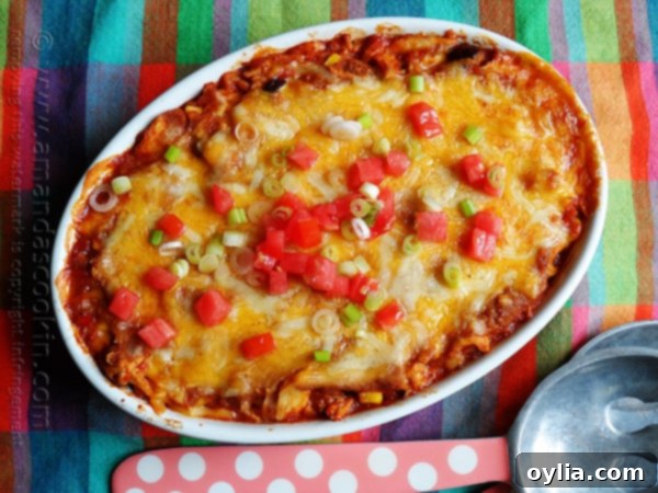 An overhead photo of a chicken tostada casserole with chopped green onions and tomatoes on top.