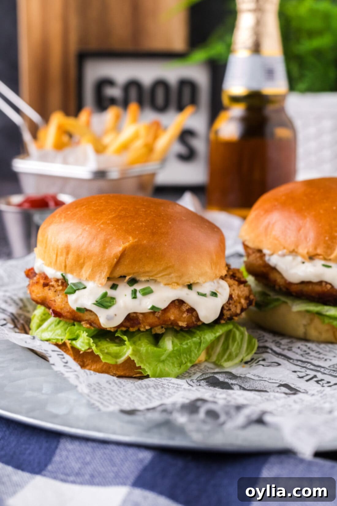 Two Fish Burgers on a platter with fries in the background, showcasing their golden, crispy exterior.