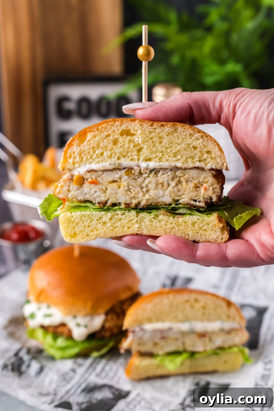 Hand holding up a Fish Burger cut in half, revealing the juicy, flavorful interior.