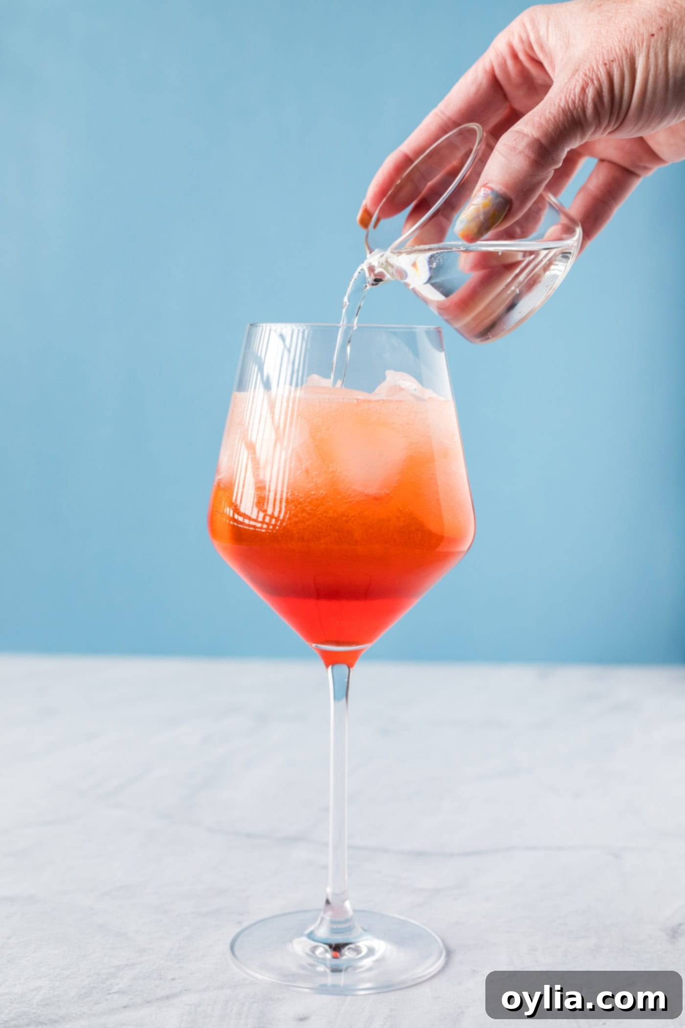 pouring club soda into aperol spritz