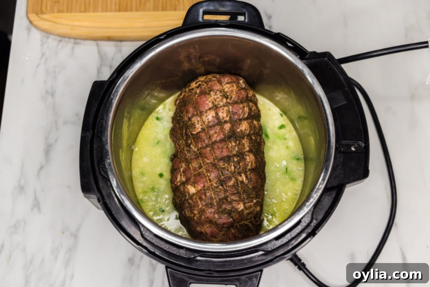 The seasoned pork roast carefully placed inside the Instant Pot, resting on the sautéed vegetables and liquid.
