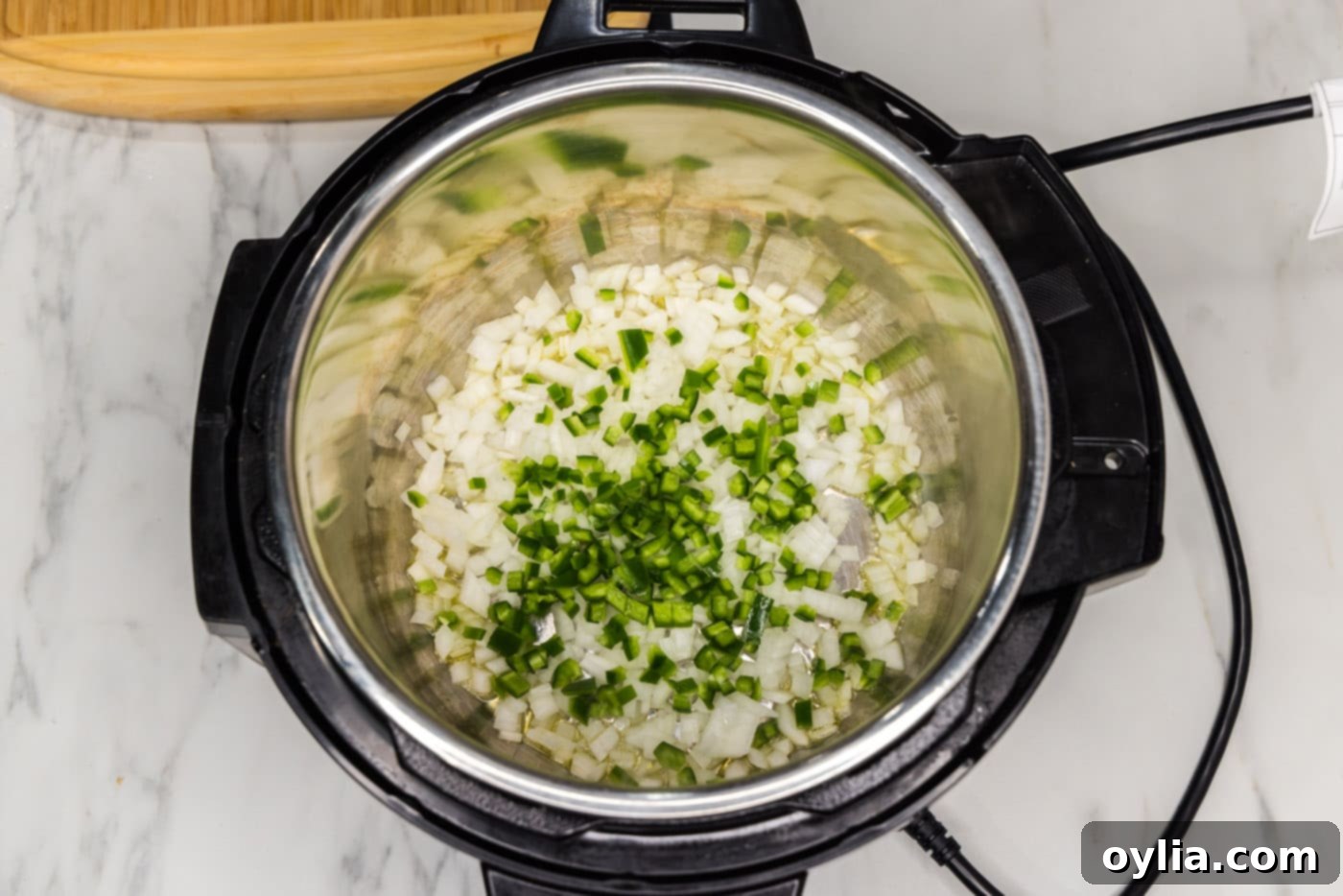 Diced jalapeno and chopped onion sizzling and sauteing in the bottom of an Instant Pot.