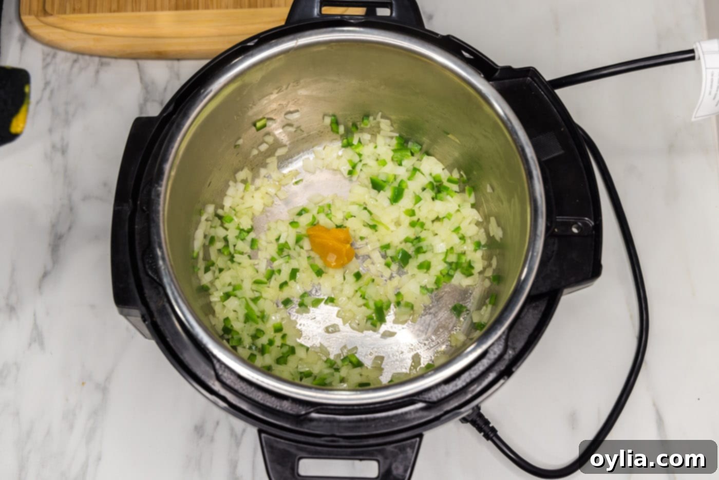 Adding chicken base to the sautéed vegetables in the Instant Pot, preparing to stir and deglaze.