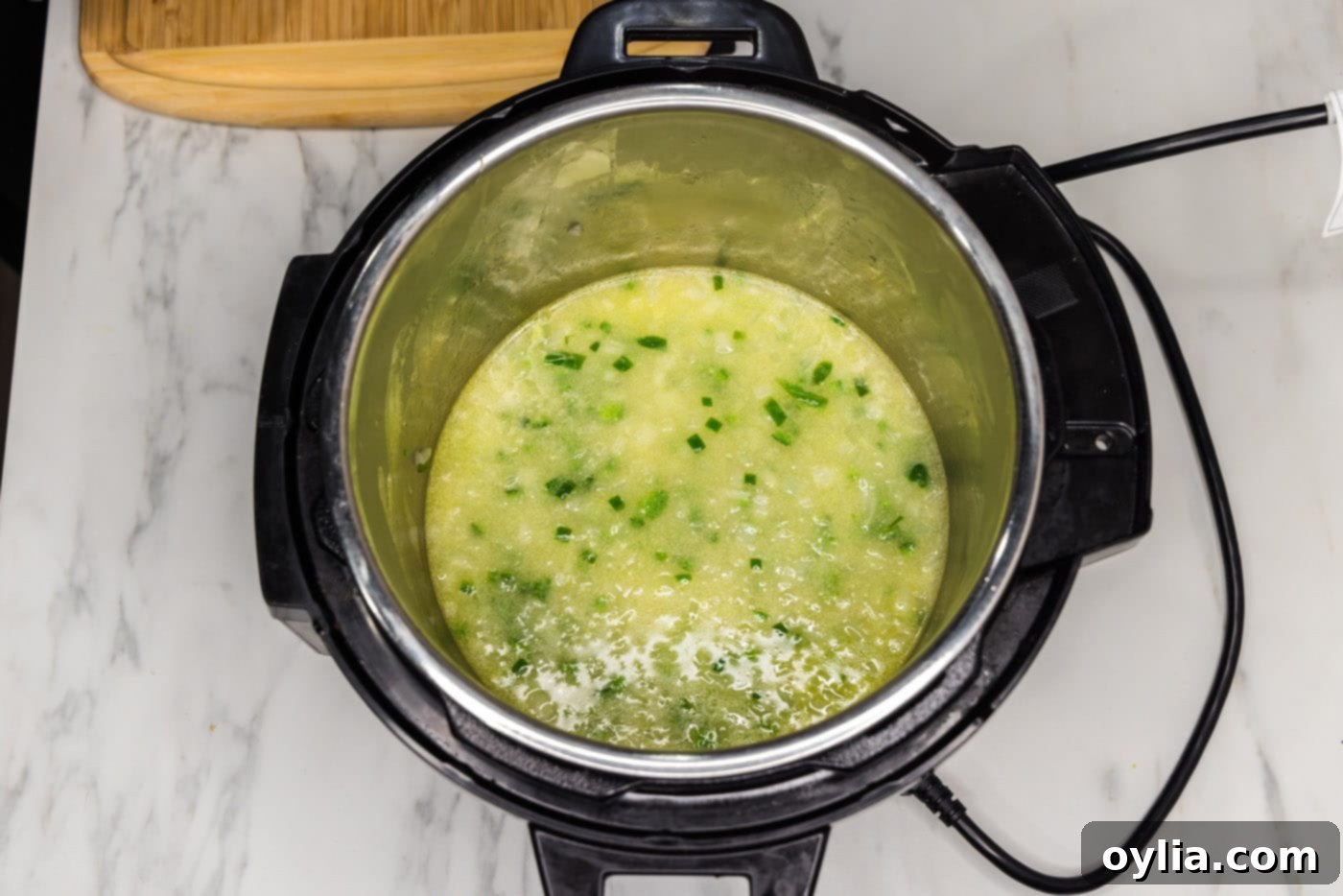 The Instant Pot liner filled with water, chicken base, and sautéed vegetables, ready for the pork.