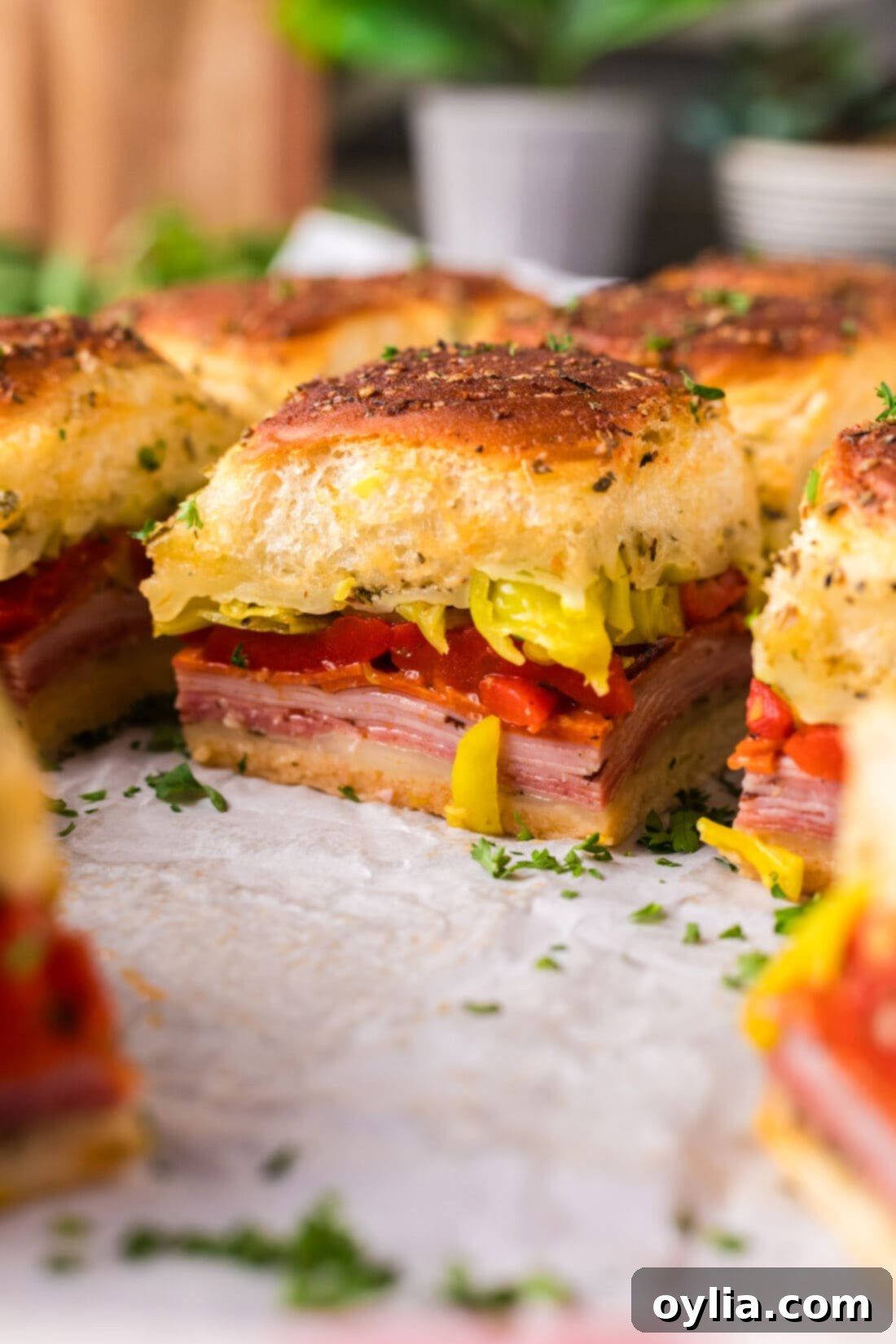 Close up photo of Italian Sliders on parchment paper, showcasing the melted cheese and toppings