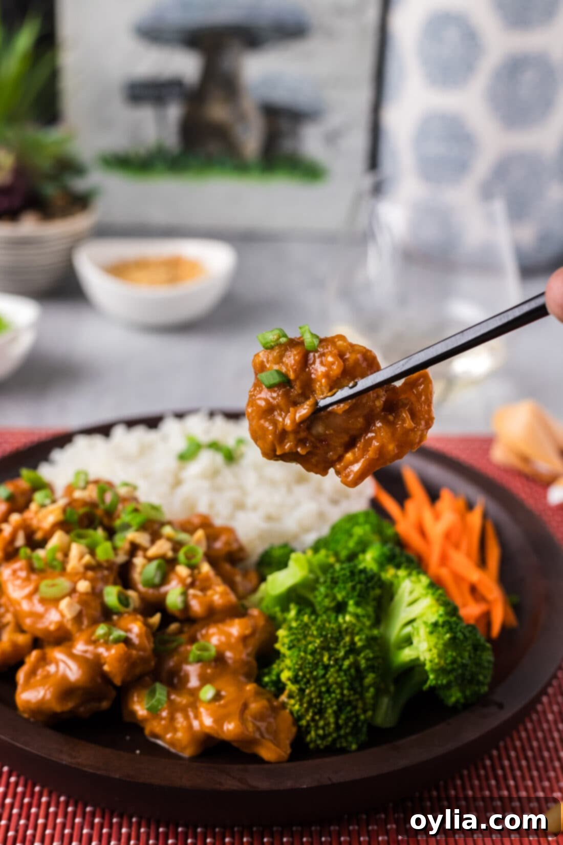 Chopsticks holding up a piece of Peanut Butter Chicken