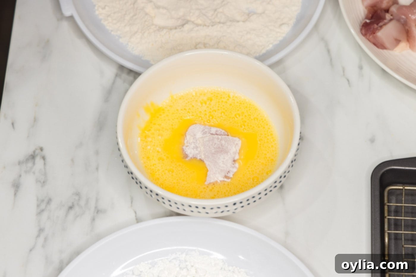 coating flour dredged chicken pieces in egg