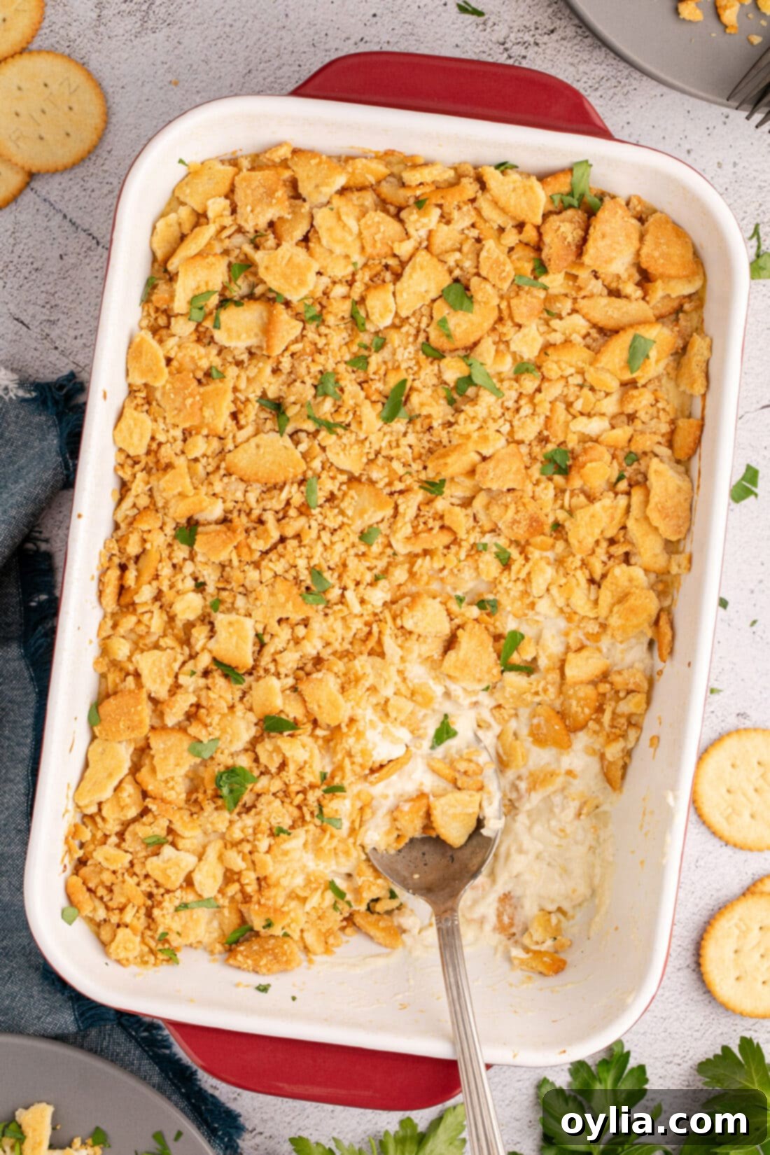 Overhead photo of a Ritz Cracker Chicken Casserole in a casserole dish with a spoon in it, showcasing its golden, bubbly topping and creamy interior.