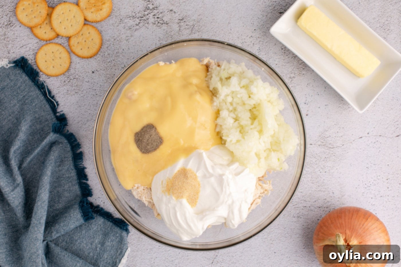 A large mixing bowl filled with the creamy chicken casserole mixture, including cream of chicken soup, sour cream, onion, shredded chicken, and seasonings.