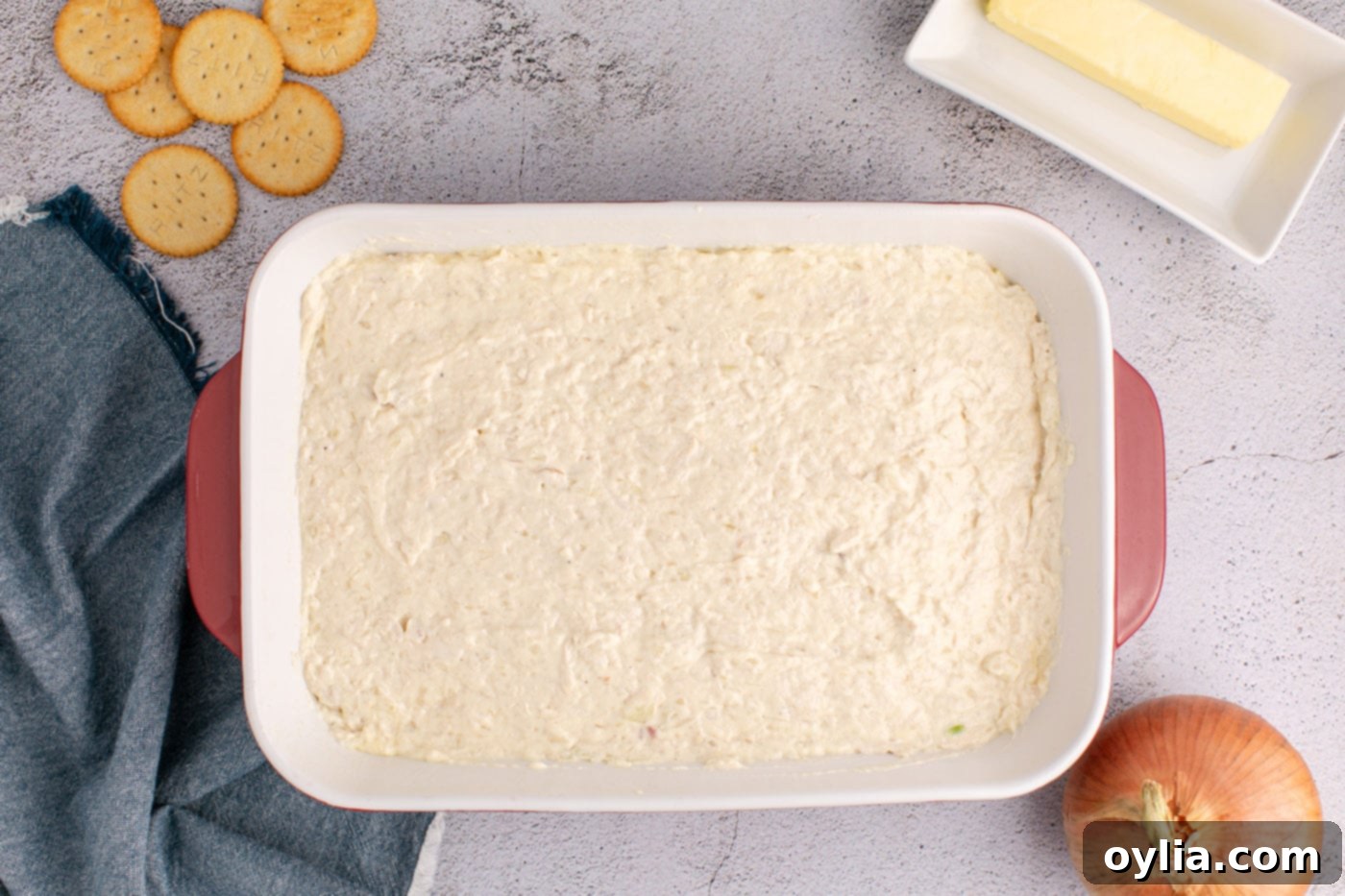 The creamy chicken casserole filling spread evenly in a 9x13 inch baking dish, ready for the topping.