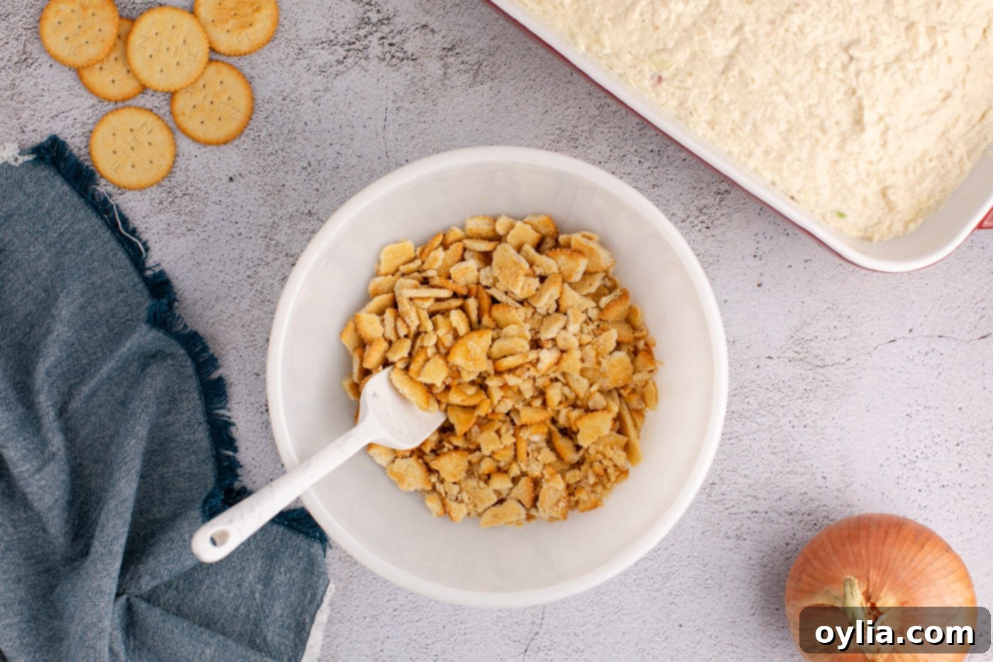A small bowl holding crushed Ritz crackers coated in melted butter, ready to be spread over the casserole.