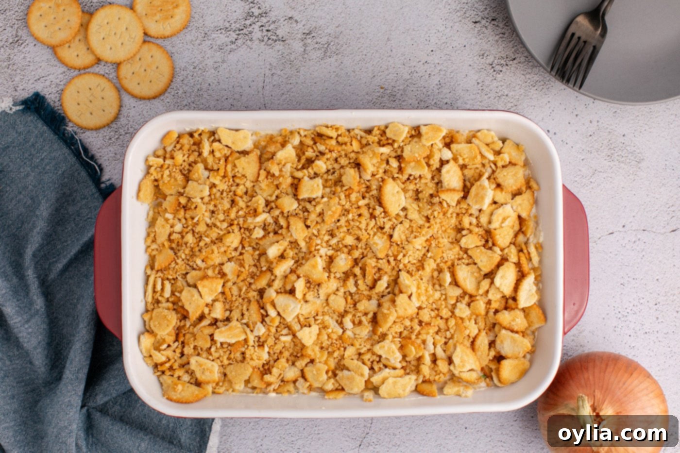 An overhead view of the Ritz cracker chicken casserole in the baking dish, with the crushed Ritz cracker topping evenly distributed before baking.