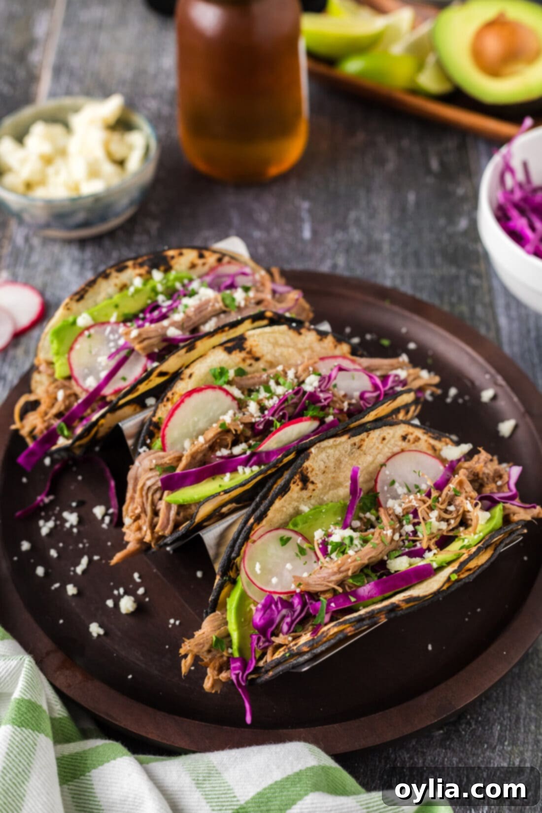 Ultimate Pulled Pork Tacos 6 Three finished Pulled Pork Tacos on a white plate, ready to be served, with a lime wedge for garnish.