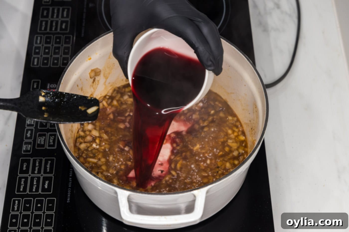 pouring red wine into braising liquid