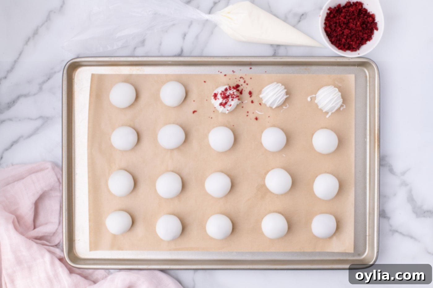 Sprinkling reserved red velvet cake crumbs on top of drizzled cake balls