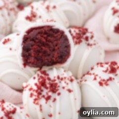 Close up photo of Red Velvet Cake Balls with one cut in half, showcasing the moist cake and frosting