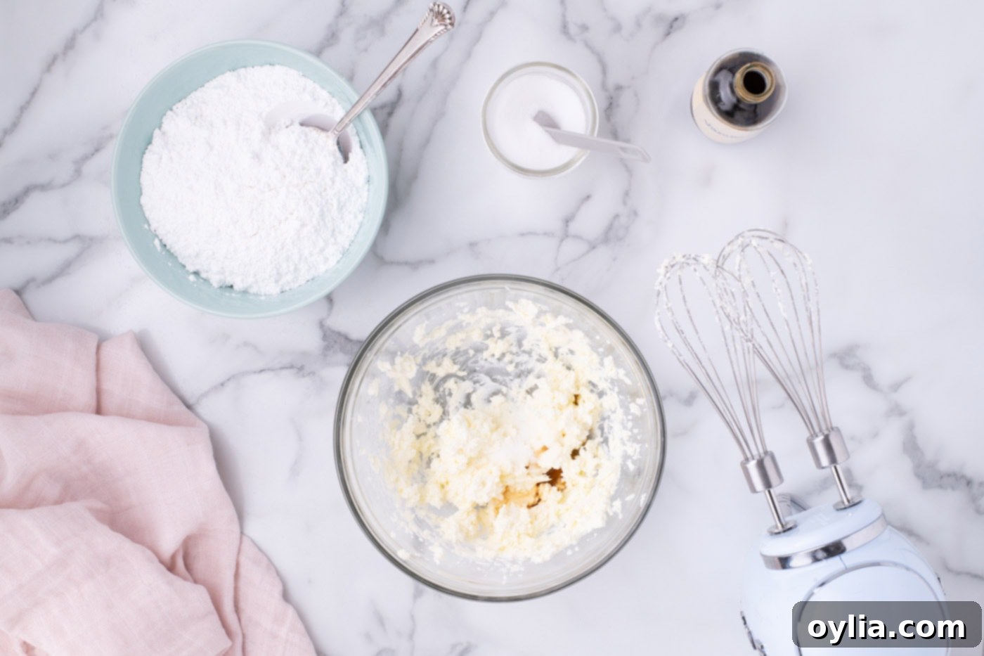 Softened butter and cream cheese being beaten together in a mixing bowl until light and fluffy