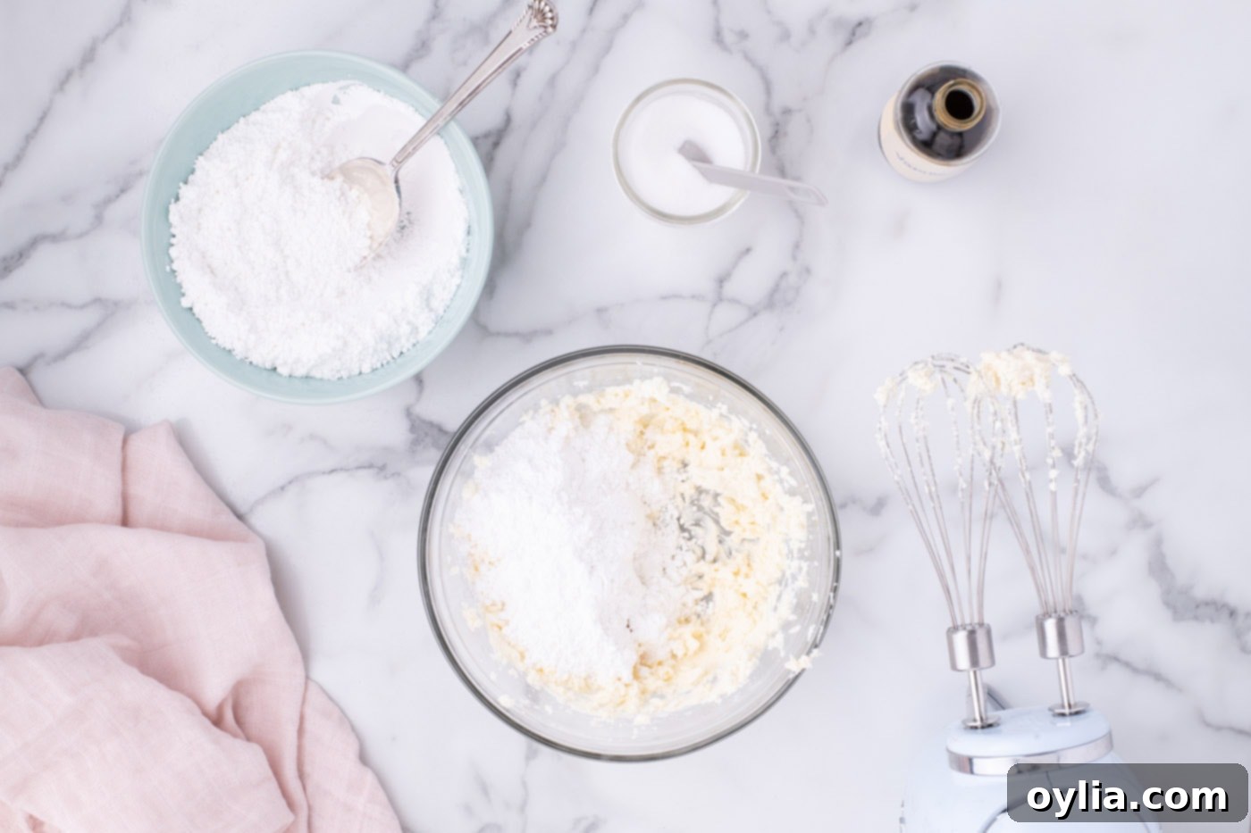 Adding powdered sugar gradually to the cream cheese and butter mixture for frosting