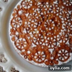 A beautiful Merryfield apple cake, artfully dusted with powdered sugar, resting on a decorative white platter.