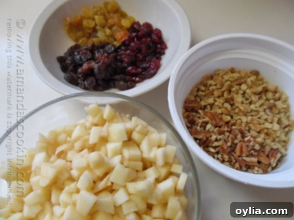 All the dry ingredients for Merryfield Apple Cake, including chopped apples, nuts, and raisins, measured and combined in a single mixing bowl.