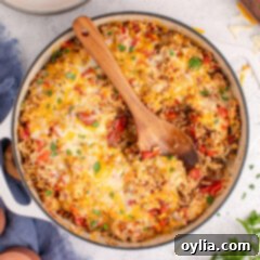 Hearty Stuffed Pepper Bake 13 Stuffed Pepper Casserole in a dutch oven with a spoon, highlighting the cheesy topping and hearty ingredients.