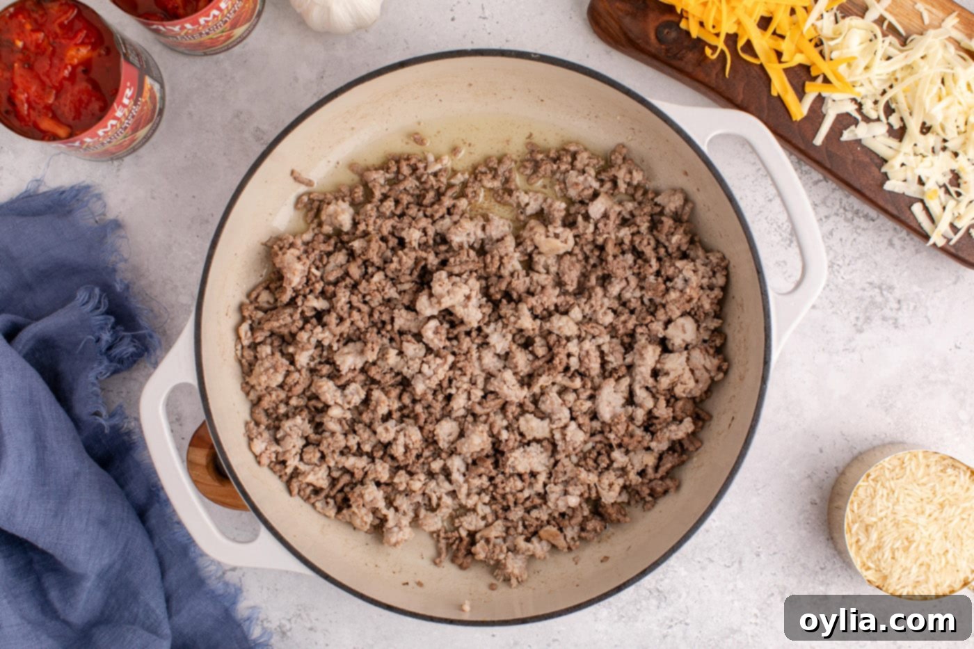 Ground beef and Italian sausage browning in a large skillet, releasing savory aromas.